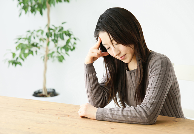 机に肘を付き頭をささえる女性