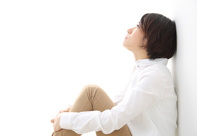 膝を抱え上を見上げる女性